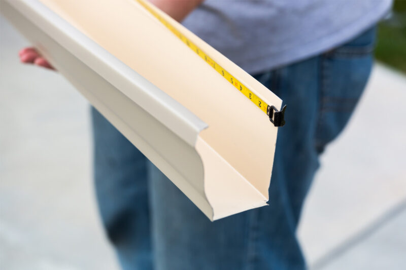 Person Measuring Seamless Gutters In Wichita Ks