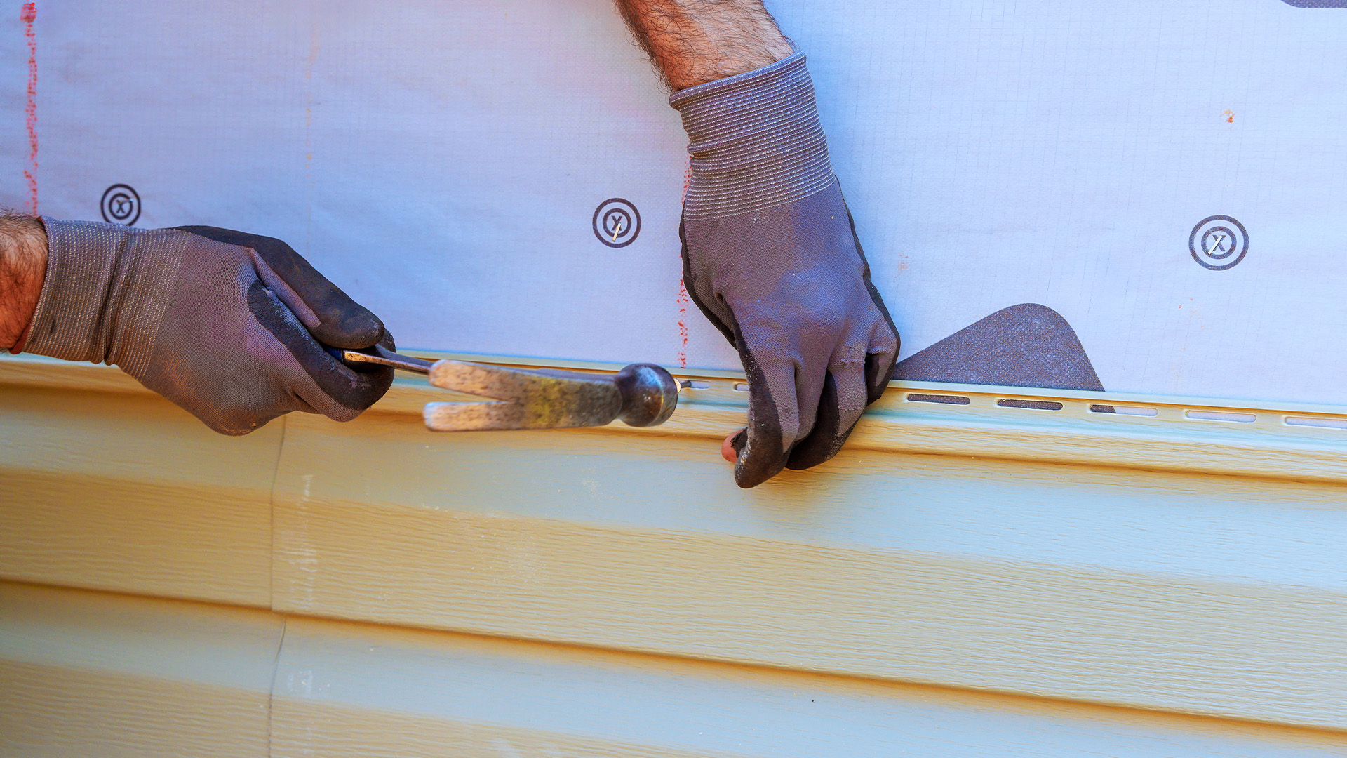 Worker Installing Vinyl Siding On Modern Home