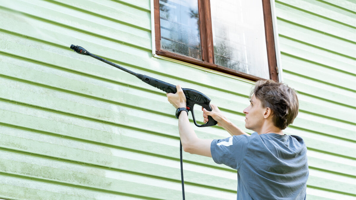 Homeowner Cleaning Home Siding With Pressure Washer In Wichita Ks