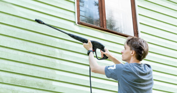 Homeowner Cleaning Home Siding With Pressure Washer In Wichita Ks